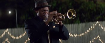 Movie still from “Cut Throat City” (2020), directed by RZA – A man in a suit and hat playing a trumpet; Medium shot, Low angle