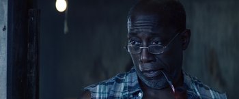 Movie still from “Cut Throat City” (2020), directed by RZA – An older man wearing glasses and a checkered shirt; Close Up shot, Low angle