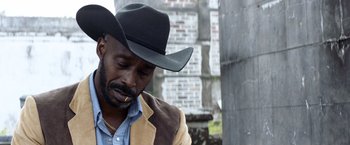 Movie still from “Cut Throat City” (2020), directed by RZA – A man in a cowboy hat is smoking a cigarette; Close Up shot, Low angle