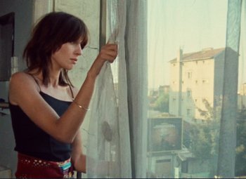 Movie still from “Celine and Julie Go Boating” (1974), directed by Jacques Rivette – A woman standing in front of a window looking outside; Medium shot, Low angle