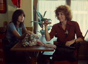 Movie still from “Celine and Julie Go Boating” (1974), directed by Jacques Rivette – Two women sitting at a table in front of a window; Medium shot, Over the shoulder angle