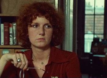 Movie still from “Celine and Julie Go Boating” (1974), directed by Jacques Rivette – A woman sitting in front of a window holding a pen; Close Up shot, Over the shoulder angle