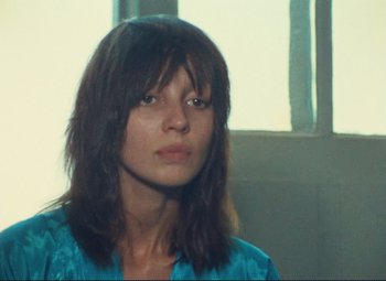 Movie still from “Celine and Julie Go Boating” (1974), directed by Jacques Rivette – A woman with long brown hair wearing a blue shirt; Close Up shot, Low angle