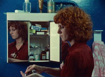 Movie still from “Celine and Julie Go Boating” (1974), directed by Jacques Rivette – A woman in a red shirt looking in a mirror; Close Up shot, Over the shoulder angle