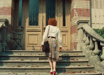 Movie still from “Celine and Julie Go Boating” (1974), directed by Jacques Rivette – A woman with red curly hair standing on the steps of a building; Wide shot, High angle