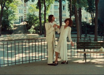Movie still from “Celine and Julie Go Boating” (1974), directed by Jacques Rivette – A man and a woman standing next to each other on a bench; Wide shot, High angle