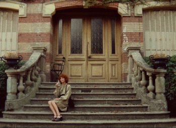 Movie still from “Celine and Julie Go Boating” (1974), directed by Jacques Rivette – A woman sitting on the steps of an old building; Wide shot, Low angle
