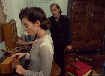 Movie still from “Celine and Julie Go Boating” (1974), directed by Jacques Rivette – A man and a woman standing in front of a chair; Medium shot, Over the shoulder angle