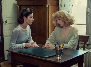 Movie still from “Celine and Julie Go Boating” (1974), directed by Jacques Rivette – Two women sitting at a table talking to each other; Medium shot, High angle