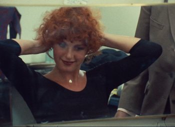 Movie still from “Celine and Julie Go Boating” (1974), directed by Jacques Rivette – A woman with red curly hair sitting in front of a bathroom mirror; Close Up shot, Over the shoulder angle