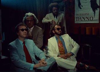 Movie still from “Celine and Julie Go Boating” (1974), directed by Jacques Rivette – A group of men in suits and ties sitting in a room; Wide shot, High angle