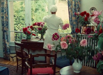 Movie still from “Celine and Julie Go Boating” (1974), directed by Jacques Rivette – A woman standing at a dining room table looking out the window; Wide shot, High angle
