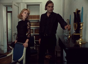 Movie still from “Celine and Julie Go Boating” (1974), directed by Jacques Rivette – A man and a woman standing next to each other in a room; Medium shot, Low angle