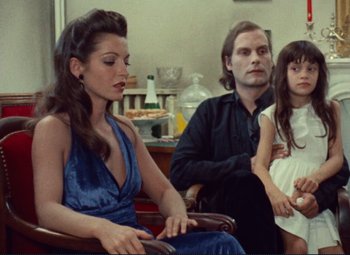 Movie still from “Celine and Julie Go Boating” (1974), directed by Jacques Rivette – A man and a woman sitting next to a little girl; Medium shot, Over the shoulder angle