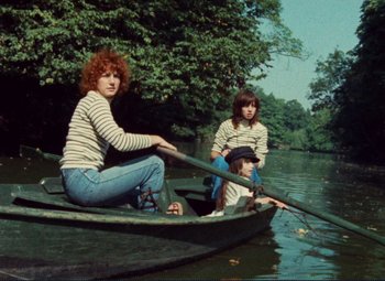 Movie still from “Celine and Julie Go Boating” (1974), directed by Jacques Rivette – Two women are sitting in a boat on the water; Wide shot, High angle