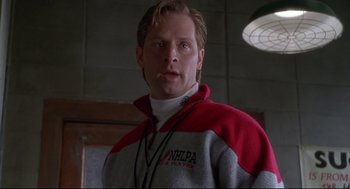 Movie still from “D3: The Mighty Ducks” (1996), directed by Robert Lieberman – A man in a red and white jacket standing in front of a wall; Close Up shot, Low angle