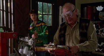 Movie still from “D3: The Mighty Ducks” (1996), directed by Robert Lieberman – A man and a young boy working on a project together; Medium shot, Low angle