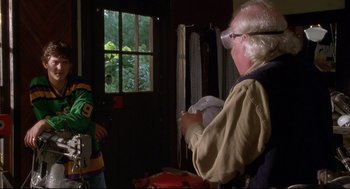 An older man is looking at a young man in a green shirt