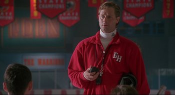 Movie still from “D3: The Mighty Ducks” (1996), directed by Robert Lieberman – A man holding a cell phone while standing in front of a crowd; Close Up shot, Low angle