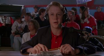 Movie still from “D3: The Mighty Ducks” (1996), directed by Robert Lieberman – A young man wearing headphones while sitting in front of a microphone; Close Up shot, Low angle