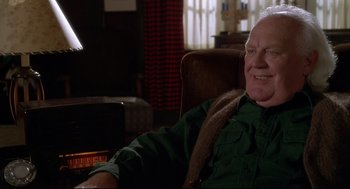 Movie still from “D3: The Mighty Ducks” (1996), directed by Robert Lieberman – An older man sitting in a chair in front of a television; Close Up shot, Over the shoulder angle