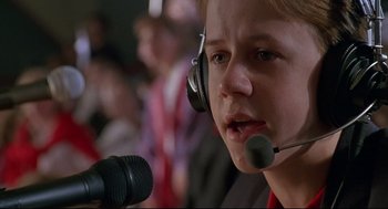 Movie still from “D3: The Mighty Ducks” (1996), directed by Robert Lieberman – A young boy wearing headphones and holding a microphone; Close Up shot, Low angle
