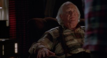 Movie still from “D3: The Mighty Ducks” (1996), directed by Robert Lieberman – An older man sitting in a chair with his hands in his lap; Close Up shot, Low angle
