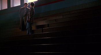 Movie still from “D3: The Mighty Ducks” (1996), directed by Robert Lieberman – Two people are standing on some steps in the dark; Wide shot, Low angle