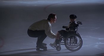 Movie still from “D3: The Mighty Ducks” (1996), directed by Robert Lieberman – A man kneeling down next to a girl in a wheelchair; Medium shot, Low angle
