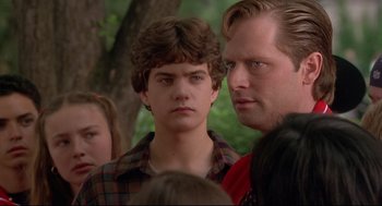 Movie still from “D3: The Mighty Ducks” (1996), directed by Robert Lieberman – A man and a woman standing next to each other in front of a tree; Close Up shot, Over the shoulder angle