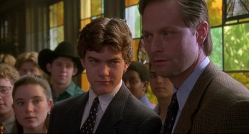 Movie still from “D3: The Mighty Ducks” (1996), directed by Robert Lieberman – A group of men standing next to each other in front of a stained glass window; Close Up shot, Over the shoulder angle
