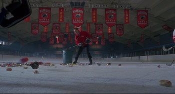 Movie still from “D3: The Mighty Ducks” (1996), directed by Robert Lieberman – A man in a red shirt is playing hockey; Extreme Wide shot, Low angle