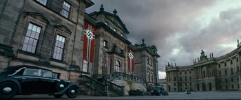Movie still from “Dad's Army” (2016), directed by Oliver Parker – A building that has nazi flags on the side of it; Extreme Wide shot, Low angle