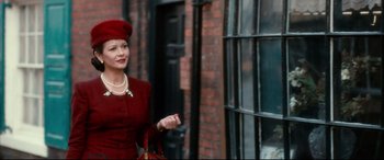 Movie still from “Dad's Army” (2016), directed by Oliver Parker – A woman in a red dress standing in front of a window; Medium shot, Over the shoulder angle