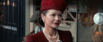 Movie still from “Dad's Army” (2016), directed by Oliver Parker – An older woman wearing a red hat and pearls; Close Up shot, Over the shoulder angle