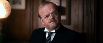 Movie still from “Dad's Army” (2016), directed by Oliver Parker – A man with a beard wearing a suit and tie; Close Up shot, Low angle