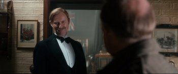 Movie still from “Dad's Army” (2016), directed by Oliver Parker – A man in a tuxedo looking at himself in the mirror; Medium shot, Over the shoulder angle