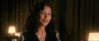 Movie still from “Dad's Army” (2016), directed by Oliver Parker – A beautiful woman with long curly brown hair and red lipstick; Close Up shot, Over the shoulder angle