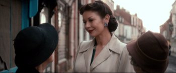Movie still from “Dad's Army” (2016), directed by Oliver Parker – A woman in a beige coat and a blue and white necklace; Close Up shot, Over the shoulder angle