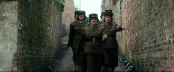 Movie still from “Dad's Army” (2016), directed by Oliver Parker – A group of women dressed in uniforms walking down a street; Medium shot, Low angle