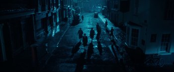 Movie still from “Dad's Army” (2016), directed by Oliver Parker – A group of people walking down a street at night; Extreme Wide shot, High angle