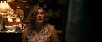 Movie still from “Dad's Army” (2016), directed by Oliver Parker – A woman in a brown apron is looking at the camera; Medium shot, Over the shoulder angle