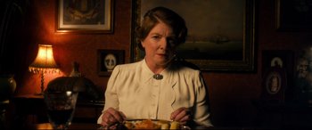 Movie still from “Dad's Army” (2016), directed by Oliver Parker – An older woman sitting in front of a plate of food; Medium shot, Low angle