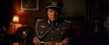 Movie still from “Dad's Army” (2016), directed by Oliver Parker – A woman in a military uniform holding a plate of food; Medium shot, High angle