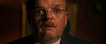 Movie still from “Dad's Army” (2016), directed by Oliver Parker – A person wearing a suit and glasses; Close Up shot, Low angle