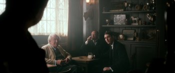 Movie still from “Dad's Army” (2016), directed by Oliver Parker – A group of men sitting at a table in front of a window; Medium shot, Over the shoulder angle