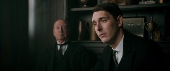 Movie still from “Dad's Army” (2016), directed by Oliver Parker – A man in a suit and tie next to another man in a suit and tie; Close Up shot, Over the shoulder angle