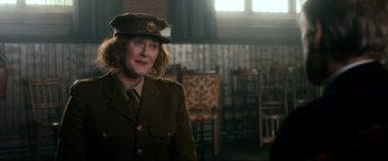 Movie still from “Dad's Army” (2016), directed by Oliver Parker – A woman in a military uniform is smiling for the camera; Medium shot, Over the shoulder angle