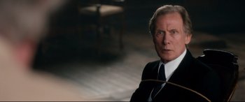 Movie still from “Dad's Army” (2016), directed by Oliver Parker – An older man wearing a suit and tie; Close Up shot, Over the shoulder angle