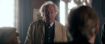Movie still from “Dad's Army” (2016), directed by Oliver Parker – An older man in a tan jacket and a red tie; Close Up shot, Over the shoulder angle